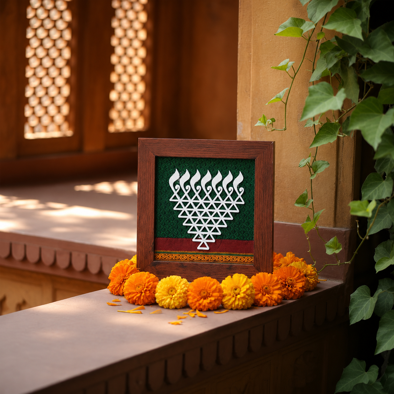 Decorative frame with a geometric design surrounded by marigold flowers on a ledge.