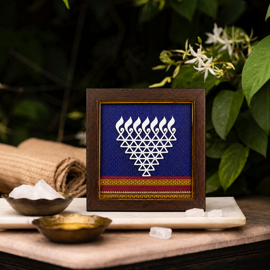 Framed artwork with geometric design on a wooden surface with leaves in the background