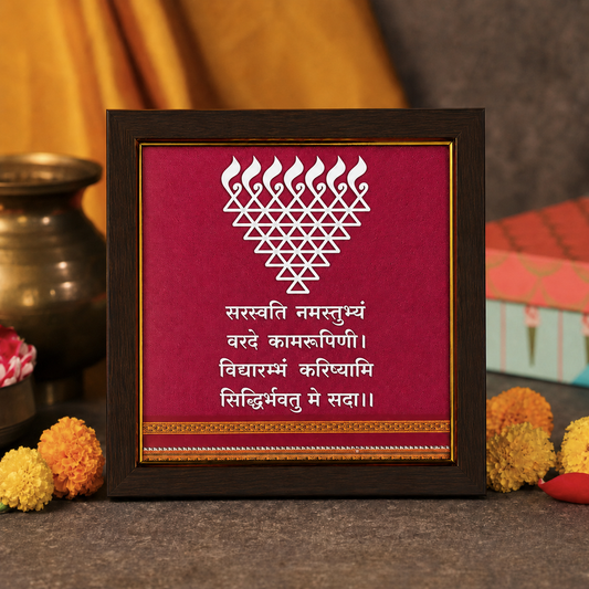 Framed decorative piece with a white design on a red background, placed on a surface with decorative items.